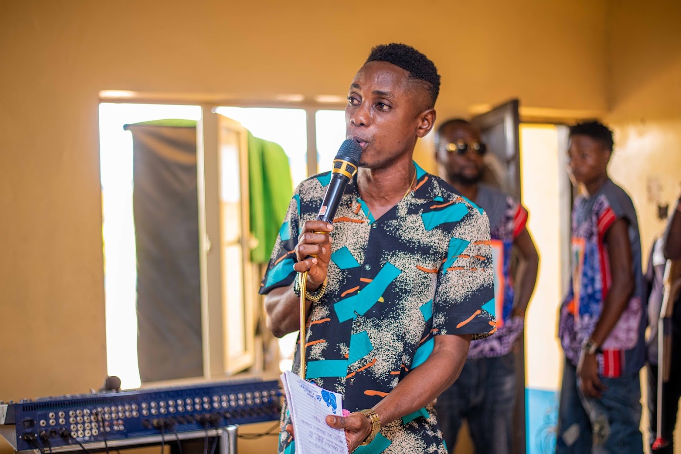 A young man singing into a microphone at a foundation programme.